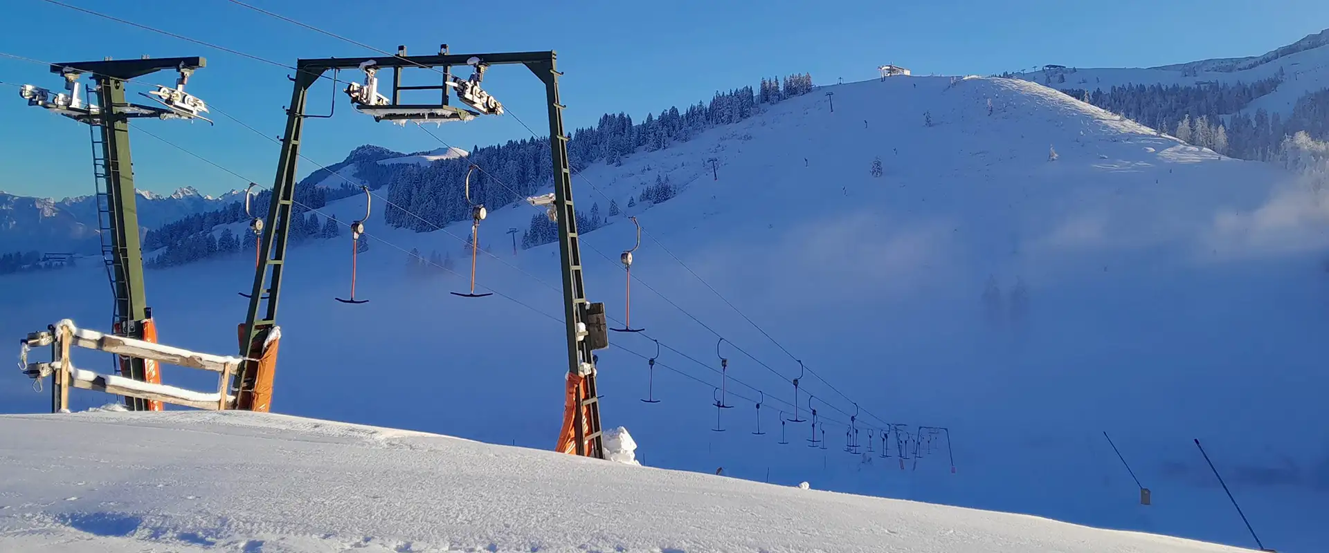 Verschneite Piste mit Schlepplift in Bayrischzell – Morgenstimmung im Skigebiet der Skischule und Snowboardschule Bayrischzell.